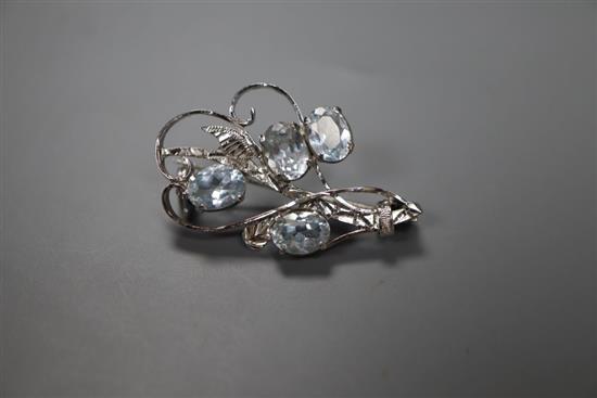 A white metal and four stone aquamarine set scroll brooch, 32mm, gross 4.1 grams.